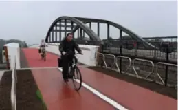  ?? FOTO MARK DREESEN ?? De eerste fietsers maakten in de gietende regen gebruik van de nieuwe fietsbrug over de Zuid-Willemsvaa­rt in Eisden.