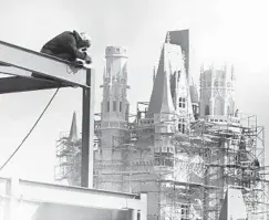  ?? ORLANDO SENTINEL FILE ?? As a welder works on the constructi­on of a restaurant in Walt Disney World’s Magic Kingdom, Cinderella Castle rises toward its completion. The iconic structure would become the focal point for the theme park.