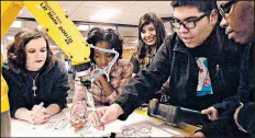  ??  ?? Andrew Elizalde, right, works with his team as he directs the robotic arm at Purdue University Northwest’s Robotics Camp.