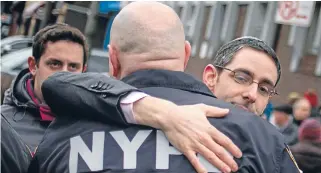  ?? Photo: REUTERS ?? Civilian support: A supporter embraces a New York Police Department officer outside the 50th Precinct Station House in Bronx.