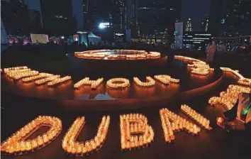  ?? Atiq ur Rehman/Gulf News ?? ■ People light candles during the Earth Hour programme organised by the Dubai Electricit­y and Water Authority at Marasi Promenade in Business Bay yesterday.