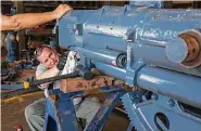  ??  ?? Ward Slack works on an anti-aircraft gun Wednesday at a warehouse in Pasadena. Volunteers are putting hundreds of hours into repairing many of the ship’s parts.