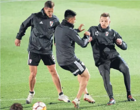  ??  ?? ► Martínez y Armani disputan el balón ante la mirada de Zuculini, durante la práctica de River Plate.