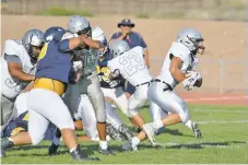  ??  ?? Capital High running back Luke Padilla, right, breaks through a hole in the Highland defense during a scrimmage.