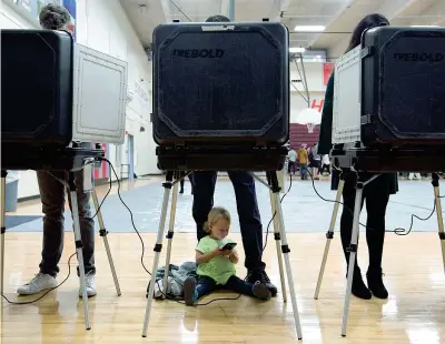  ??  ?? La piccola Sloane, 2 anni, aspetta seduta a terra accanto al padre mentre lui e gli altri elettori votano in un seggio di Atlanta, in Georgia