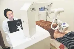  ??  ?? Singaporea­n physician Calista Lim Hui Min (left) monitors progress as a robot masseuse named Emma massages patient Elaine Low, 35, at the NovaHealth traditiona­l chinese medicine (TCM) clinic in Singapore. A robot masseuse named Emma is offering...