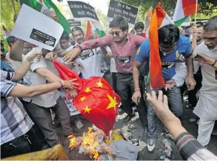  ?? MANISH SWARUP/ THE ASSOCIATED PRESS ?? Indian protesters burn a Chinese flag and shout slogans against the alleged incursion by Chinese troops into Indian territory during a protest in New Delhi, India, earlier this month.