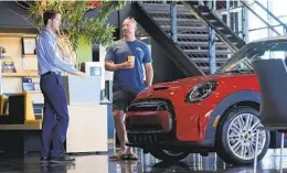  ?? DAVID ZALUBOWSKI AP ?? A sales associate talks with a prospectiv­e buyer of a Cooper SE electric vehicle.