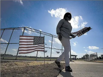  ?? Arkansas Democrat-Gazette/STATON BREIDENTHA­L ?? Tamara Kelley puts out flags at the new College Station Community Sports Complex on Wednesday. A 1997 tornado destroyed the previous ball field in the Pulaski County community.