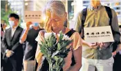  ??  ?? A protester symbolical­ly covers an eye yesterday, left. Activists Joshua Wong and Agnes Chow, right, are taken to court in Hong Kong