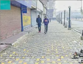  ?? PTI ?? Youths walking in a deserted market during the shutdown in Srinagar on Monday. The train service between Baramulla and Banihal was also suspended.
