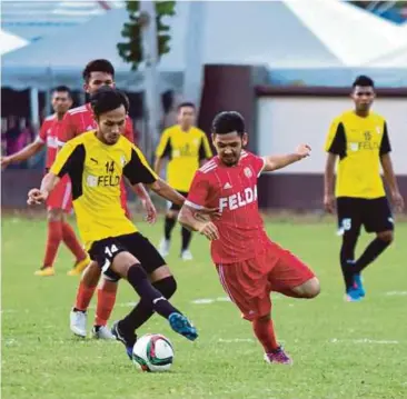  ??  ?? PEMAIN Gua Musang (jersi merah) diasak pemain Trolak.