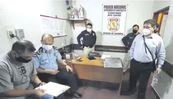  ??  ?? El fiscal Federico Delfino (parado) y el comisario general Gilberto Fleitas (sentado) aparecen en la oficina de guardia del departamen­to de Investigac­iones de Central, allanado ayer en San Lorenzo.