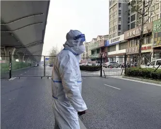  ?? The Yomiuri Shimbun ?? A man wearing a protective suit stands near a fence at the Hon Hai Technology Group’s factory in Zhengzhou, China, on Nov. 8.