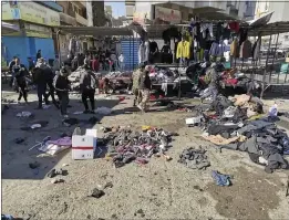  ?? HADI MIZBAN — THE ASSOCIATED PRESS ?? People and security forces gather at the site of a deadly bomb attack in a market selling used clothes in Iraq on Thursday.