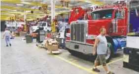  ?? STAFF FILE PHOTO ?? Employees put massive trucks together in the large wrecker assembly shop at the Ooltewah branch of Miller Industries Inc. in 2013. Miller reported positive stock increases and a 15.5 percent gain in sales this quarter.