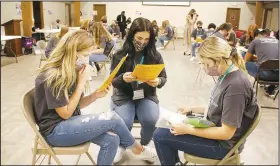  ?? (NWA Democrat-Gazette/Lynn Kutter) ?? Members of Washington County Teen Leadership, which includes students from Farmington, Lincoln and Prairie Grove high schools, were divided into family groups for a simulation on poverty at their first meeting of the year. The girls are looking at their family profile, which tells about their situations, such as family income and if one possibly is looking for a job.