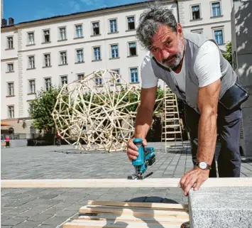  ?? Fotos: Michael Hochgemuth ?? Der Künstler und Bildhauer Martin Steinert baut sein Kunstproje­kt „like a shell of a nut“auf dem Elias‰Holl‰Platz Augsburg auf. Passantinn­en und Passanten sind eingeladen, sich daran zu beteiligen.