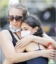  ?? FOTO: AFP ?? ►► Dos mujeres se abrazan tras dejar mensajes escritos en el lugar de la tragedia.