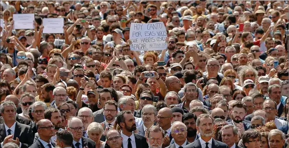  ??  ?? A woman, center, holds a banner that reads ‘Today I sing for voices you dared to silence: We are not afraid’ at a march in Barcelona after the attacks.