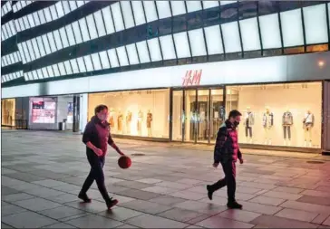  ?? AFP ?? A man wearing a protective facemask walks while playing with a basketball ball at a nearly empty shopping mall in Beijing in February.