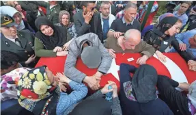  ??  ?? Relatives of Turkish soldier Nuri Sener, killed in a helicopter crash in Sirnak, Turkey, on Wednesday, mourn over his coffin during his funeral Thursday in Istanbul. At least 13 soldiers were reported killed in the accident. ERDEM SAHIN, EUROPEAN...