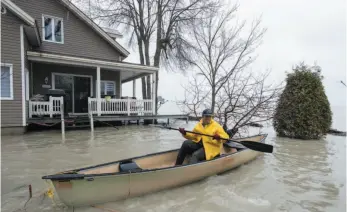  ?? CP PHOTO ?? France Bellemare paddles her canoe away from her flooded house along the St. Lawrence River in Yamachiche , Que. on Friday.