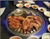  ?? ANN TATKO-PETERSON — STAFF ?? A teriyaki pork chop, honey chicken and unmarinate­d shrimp grill at a table.