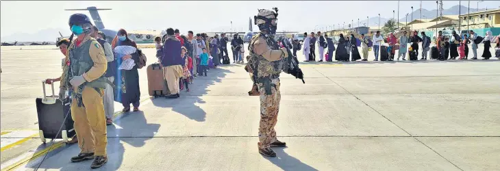  ?? REUTERS ?? Afghan evacuees desperate to flee the Taliban regime queue up before boarding an Italian military aircraft during an airlift operation at the internatio­nal airport in Kabul, Afghanista­n.