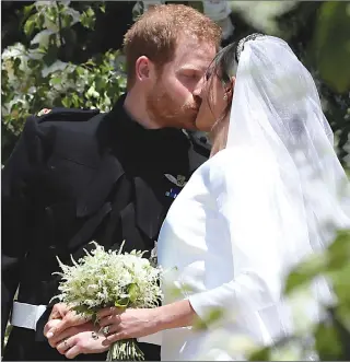  ?? Associated Press photos ?? Meghan Markle and Prince Harry kiss on the steps of St. George’s Chapel at Windsor Castle following their wedding in Windsor Castle in Windsor, near London, England, Saturday.