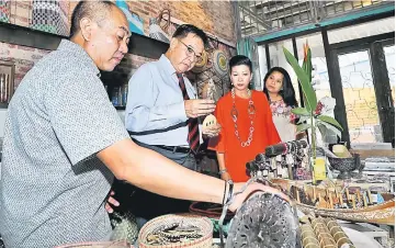  ?? — Photo by Chimon Upon ?? Abdul Karim (third right), flanked by (from left) Rentap, Rosemarie and Zuraini, looks at the souvenirs on sale at the Marian Boutique Lodging House.