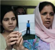  ?? NARINDER NANU/AFP/GETTY IMAGES ?? Suman Sharma, right, with her daughter Rashmi, holds a photograph of her son Atul Sharma, one of 18 missing Indian Navy sailors on Friday.