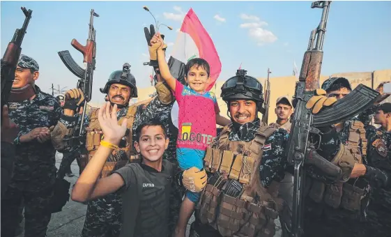  ?? Picture: AFP ?? Members of the Iraqi federal police and children celebrate the end of military operations against Islamic State fighters in the Old City of Mosul.