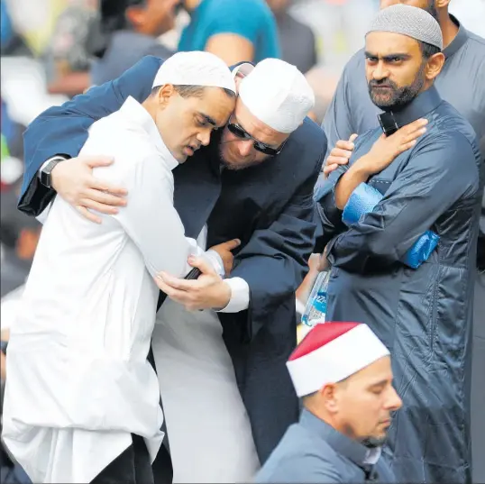  ?? Photo / AP ?? Muslim men embrace during Friday prayers at Hagley Park in Christchur­ch yesterday. People across New Zealand observed the Muslim call to prayer and two minutes’ silence.