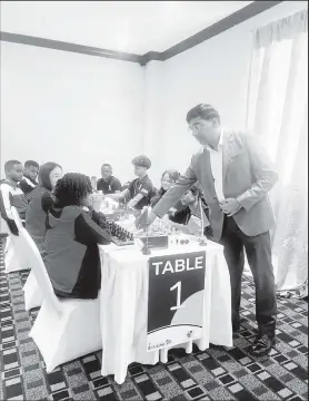  ?? ?? FIDE Deputy President, Grand Master Viswanatha­n Anand, makes the ceremonial first move at the board of Guyana’s (Team 2) Aditi Joshi (right) and Trinidad & Tobago’s Zara La Fleur