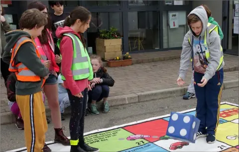  ??  ?? Educate Together pupil Oran Hogan throwing the dice in the Green Schools Travel Game at the school’s action day for its Green Travel Flag.