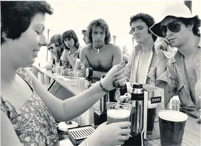  ??  ?? Barecheste­d and unbuttoned customers for Clare Laver as she pulls pints to quench their thirst in the refreshmen­t tent at Royal Birkdale during the Open