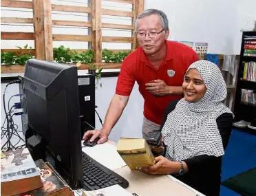  ??  ?? Agents of change: Khoo showing Kulsanofer how to work the library’s book lending system at their community library in Taman Subang, Selangor.