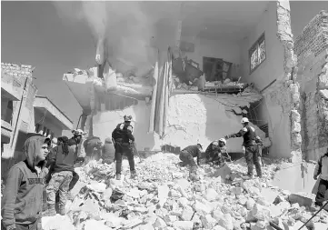  ??  ?? People and civil defence personnel remove rubble as they look for survivors at a damaged site after an air strike on rebel-held Idlib city, Syria. — Reuters photo