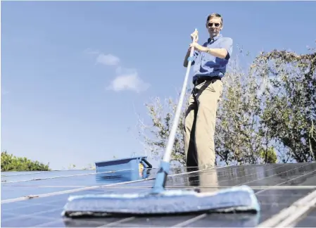  ?? MATIAS J. OCNER mocner@miamiheral­d.com ?? Phil Stoddard, chair of the Green Corridor, cleans the solar panels on his roof on Jan. 31 in South Miami.