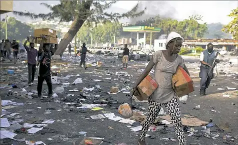  ?? Dieu Nalio Chery/Associated Press ?? People carry merchandis­e Sunday from the Delimart supermarke­t complex that was burned during two days of protests against a planned hike in fuel prices in Port-au-Prince, Haiti.