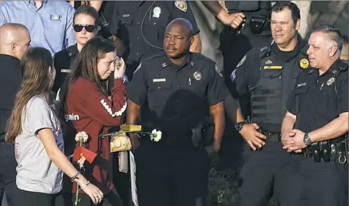  ??  ?? Marjory Stoneman Douglas High School students return to school greeted by police and well-wishers Wednesday in Parkland, Fla.