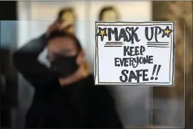  ?? MATT SLOCUM — THE ASSOCIATED PRESS ?? Manager Yllka Murati waits for a delivery driver to pick up takeout orders behind a partition displaying a sign to remind customers to wear a mask, at the Penrose Diner, in south Philadelph­ia.