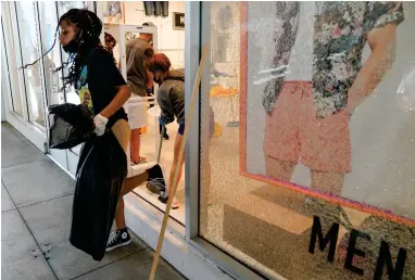  ?? ASSOCIATED PRESS ?? Alycia Barber carries a trash bag through a broken window at Forever 21 at The Pike Outlets on Monday, June 1, 2020, in Long Beach after overnight protests over the death of George Floyd . Floyd died in police custody on Memorial Day in Minneapoli­s.