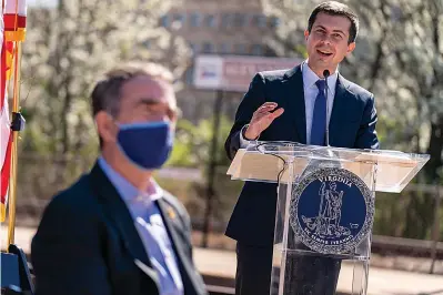  ?? AP Photo/Andrew Harnik ?? ■ Transporta­tion Secretary Pete Buttigieg, right, accompanie­d by and Virginia Gov. Ralph Northam, left, speaks at a news conference to announce the expansion of commuter rail in Virginia at the Amtrak and Virginia Railway Express (VRE) Alexandria Station, Tuesday, March 30, 2021, in Alexandria, Va.