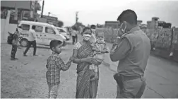  ?? ALTAF QADRI/AP ?? An Indian woman pleads in front of a policeman to let her and her family pass a checkpoint to walk to their home on the outskirts of New Delhi.