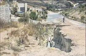  ?? Brian van der Brug Los Angeles Times ?? A GULLY has been carved into the dirt by heavy rains, claiming a portion of the sidewalk and asphalt street in the Puerto Azul developmen­t in Ensenada, Mexico.