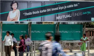  ?? — Bloomberg ?? Pedestrian­s walk past an advertisem­ent for a mutual funds campaign by the Associatio­n of Mutual Funds in India at a bus stop in Mumbai.