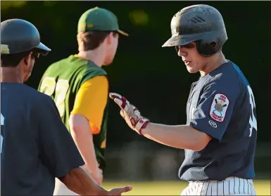  ?? DANA JENSEN/THE DAY ?? New London’s Justin Marceau, right, celebrates with the first base coach after getting a base hit during the American Legion baseball tournament game against Rocky Hill-Cromwell-Portland on Tuesday at Rotary Field in South Windsor.