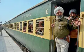  ?? AP ?? An Indian policeman and passengers from Pakistan look on from the Samjhauta Express train as it arrives in Atari, India.